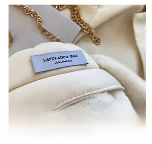 Gros plan d'un sac bandoulière en peluche blanc cassé avec chaîne dorée et étiquette