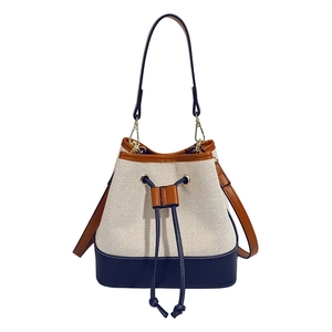 Contrast color bucket bag in off-white canvas and navy leather with brown drawstring