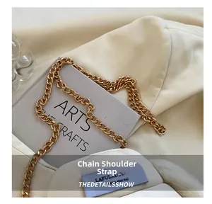 Détail de la bandoulière en chaîne dorée sur un sac en peluche blanc avec étiquette