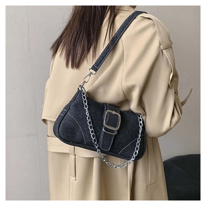 Detail of blue denim square bag with silver metal chain and buckle on trench coat