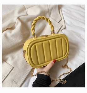 Detail of yellow quilted leather handbag with a unique twisted handle and gold chain strap