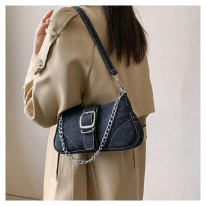 Detail of black denim handbag featuring bold silver chain strap and square buckle closure