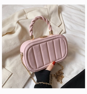 Detailed view of pink quilted handbag with woven handle and gold chain shoulder strap