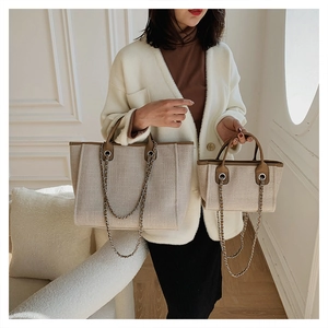 Two sizes of beige woven bucket bags with brown leather trim and silver chain straps