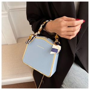 Details der hellblauen quadratischen Ledertasche mit Seidentuchgriff und goldener Hardware