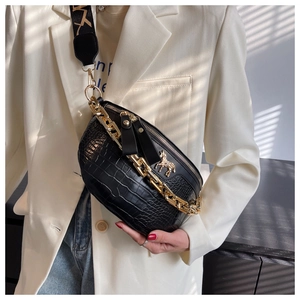 Detail of black crocodile texture chest bag with gold chain and horse charm accent