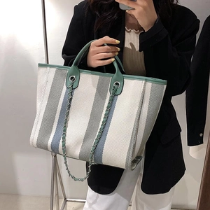 Cabas en toile rayée avec bordure en cuir et poignée en chaîne argentée sur un modèle