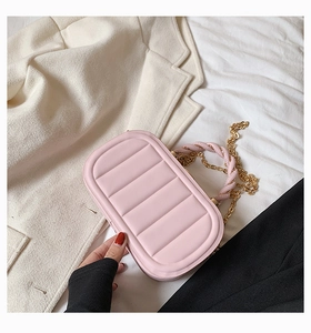 Detail of pink quilted handbag featuring twisted leather handle and gold chain strap