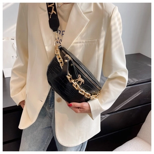 Detail of black croc-embossed crossbody bag with gold chain and unicorn charm on model