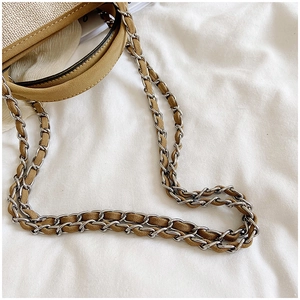 Detail of woven straw tote bag featuring leather trim and a silver chain leather strap