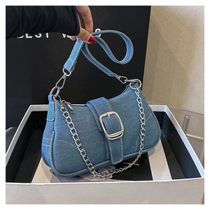 Detail of blue denim shoulder bag featuring a silver metal buckle and chain strap