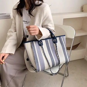 Sac cabas en toile à rayures bleues et blanches avec bandoulière chaîne sur modèle