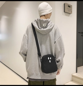 Vista street style di una borsa a tracolla nera con motivo a viso bianco su un modello