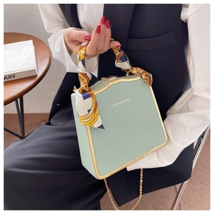 Detail der mintgrünen quadratischen Handtasche mit Goldrand und Seidenschal-Griff
