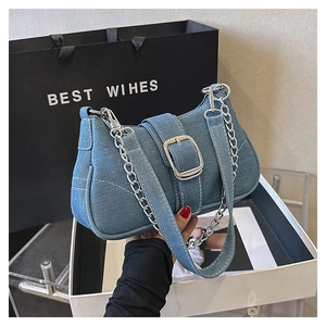 Detailed close-up of retro blue denim shoulder bag with silver buckle and metal chain