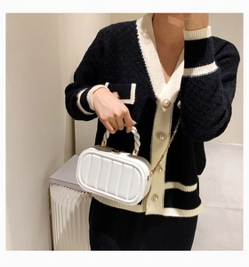 Detailed view of white textured mini bag with woven handle and gold chain strap