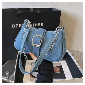 Close-up of washed denim shoulder bag with silver chain strap and large metal buckle detail