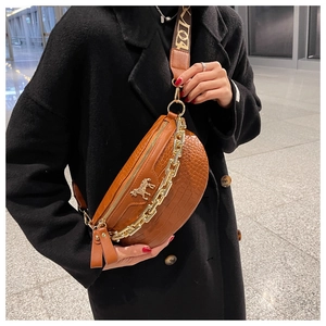 Detail of brown croc-embossed saddle bag with gold horse logo and thick chain strap