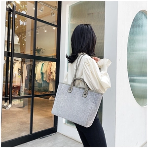 Street style view of a silver sequin tote bag with chain strap on model shoulder