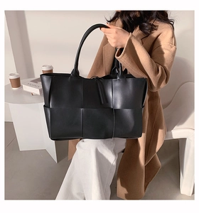 Détail d'un grand cabas tressé noir en cuir mat avec des doubles poignées souples