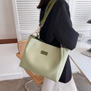 Detail of light green tote bag with brand patch and elegant gold chain shoulder strap