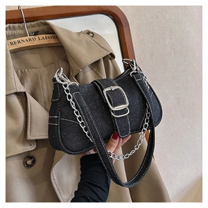 Detail of black denim handbag with white stitching, silver chain, and buckle closure