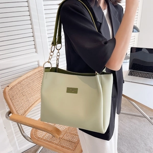 Mint green large tote bag with olive straps and gold chain detail in a chic office setting