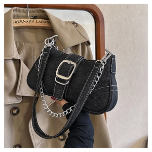 Detail of black denim handbag featuring white contrast stitching and silver hardware buckle