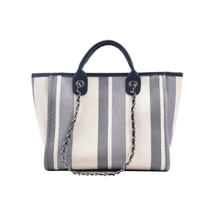 Detail of striped canvas bucket bag with navy leather trim and silver chain strap