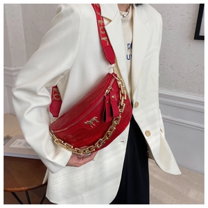 Detail of red crocodile texture waist bag with gold pegasus buckle and chunky chain