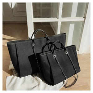 Detail of black canvas bucket tote bags with leather handles and metal chain straps