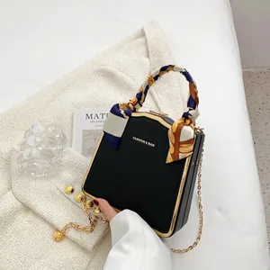 Elegante schwarze quadratische Handtasche mit Goldrahmen und Seidenschal-Griffdekor