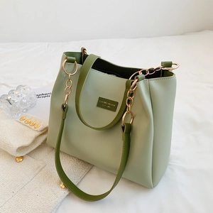 Detail of light green tote bag featuring brand tag and elegant gold chain hardware