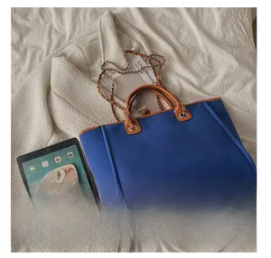 Blue canvas tote with brown leather trim shown next to iPad for size comparison