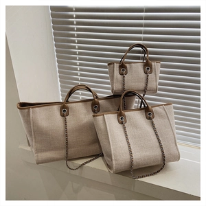 Three sizes of canvas tote bags with brown leather trim displayed on a sunlit windowsill