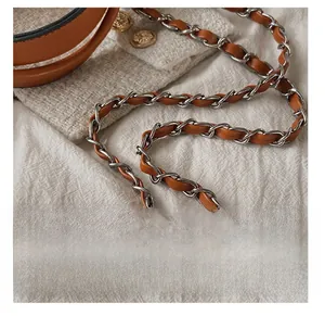 Detail of silver chain strap woven with brown leather on white tweed handbag