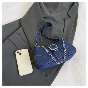Close-up of deep blue denim bag with silver buckle and chain on a suit jacket