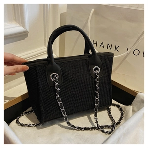 Close-up of black tweed bucket bag with silver chain strap and modern texture details