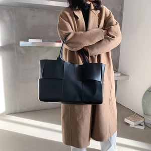Grand sac cabas tressé noir en cuir porté par un mannequin pour le style quotidien
