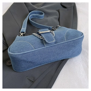 Detail of blue denim crossbody bag with silver chain and white contrast stitching