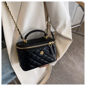 Detail einer Mini-Stepptasche mit goldenem Kamelien-Logo und Kettenriemen am Model