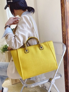 Vibrant yellow textured canvas tote bag with chain strap shown in a lifestyle setting