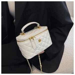 Detail der weißen gesteppten Mini-Tasche mit Blumenverschluss und Kettenriemen auf Blazer