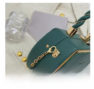 Detailed close-up of golden lobster clasp hardware and green braided handle on luxury handbag