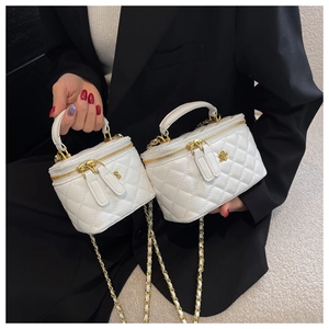 Details der weißen Mini-Eimertasche mit Steppmuster, Goldkette und Blumenornament