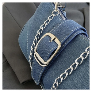 Detail of blue denim shoulder bag showing silver metal chain and textured fabric
