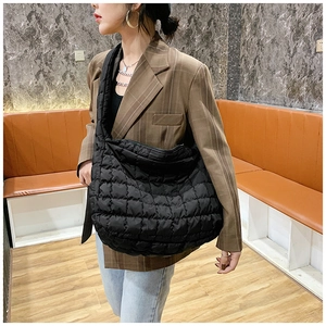 Detail of a large black quilted crescent shoulder bag with classic diamond stitching pattern