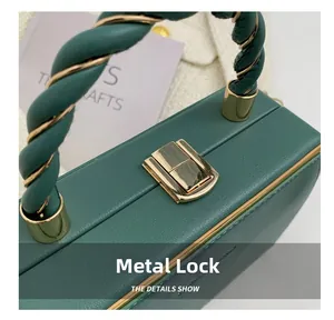 Detail of dark green textured leather handbag featuring a square golden metal lock buckle