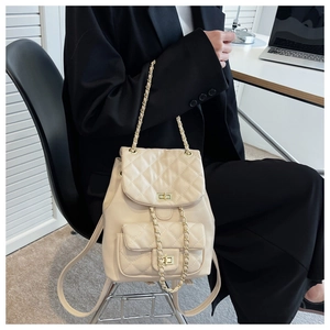 Detail of cream quilted leather backpack with gold twist lock and chain strap
