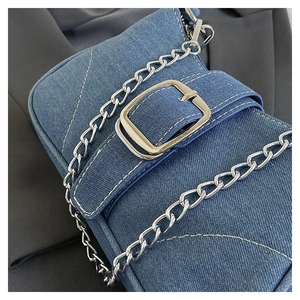 Detail of blue denim shoulder bag featuring silver chain and decorative buckle